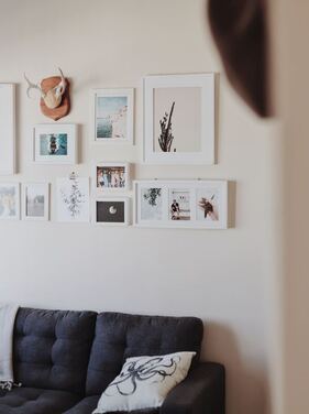 A beige wall with nine frame photos of varying sizes and shapes.